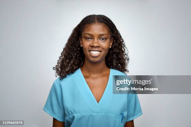 smiling female nurse over white background - vestimenta de hospital fotografías e imágenes de stock