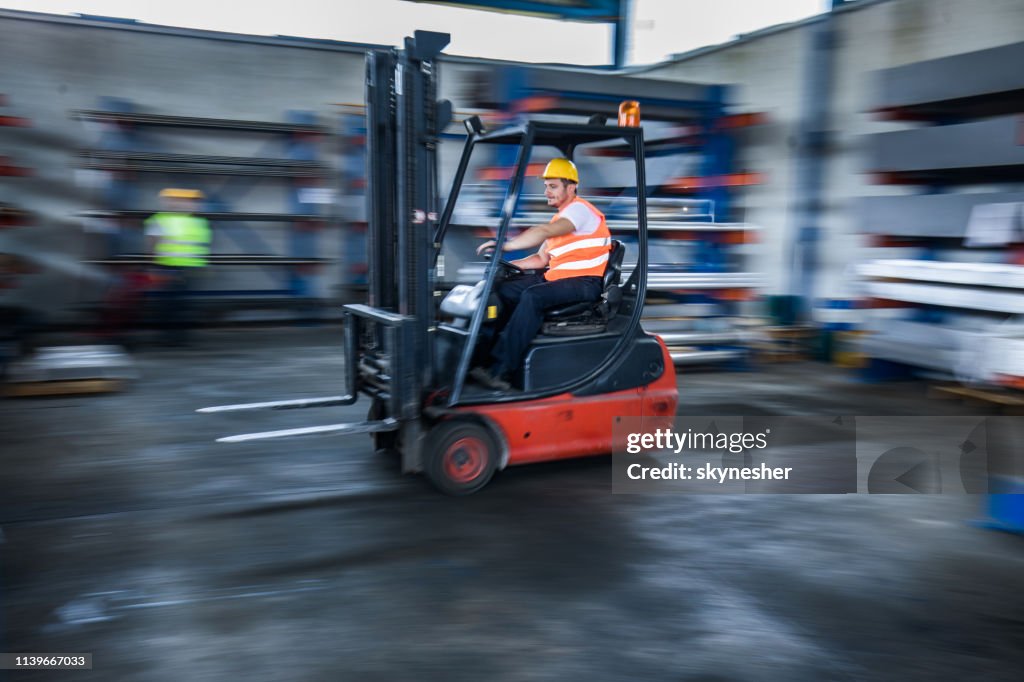 Blurred motion of manual worker in a forklift at warehouse.