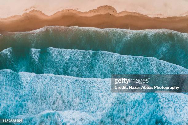 aerial view of sea waves breaking on shore. - new zealand beach stock pictures, royalty-free photos & images