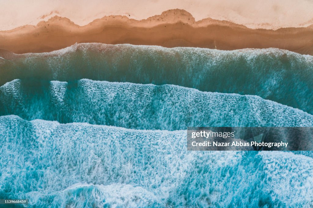 Aerial view of sea waves breaking on shore.