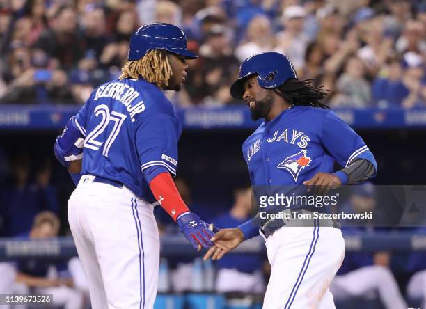Alen Hanson of the Toronto Blue Jays is congratulated by Vladimir Guerrero Jr. #27 after scoring a run in the second inning during MLB game action...