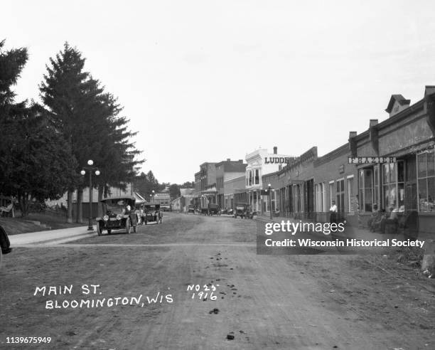 View of Main Street from the middle of the street looking down the street, Bloomington, Wisconsin, 1916. Cars are parked on either side of the...