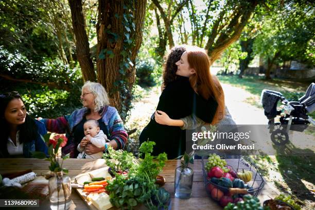 two women hugging on a garden party - picnic table park stock pictures, royalty-free photos & images