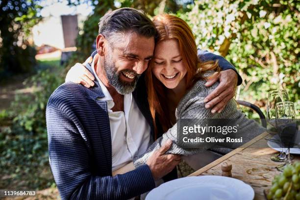 happy father and adult daughter hugging on a garden party - mature men laughing stock pictures, royalty-free photos & images