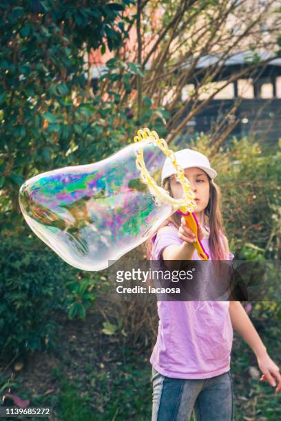 girl making large soap bubble - kind seifenblasen stockfoto's en -beelden