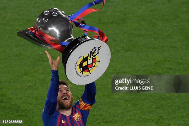 Barcelona's Argentinian forward Lionel Messi raises La Liga trophy as he celebrates becoming La Liga champions after winning the Spanish League...