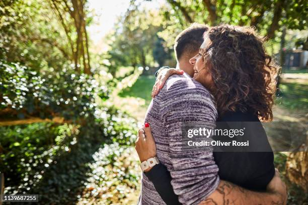 mother and adult son hugging in garden - mutter sohn erwachsen stock-fotos und bilder