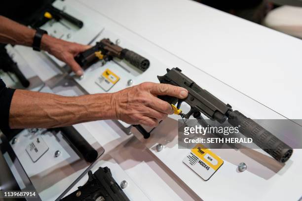 Attendees hold hand-guns equipped with surpressors duringh the National Rifle Association 2019 Annual Meetings on Saturday, April 27, 2019 at the...