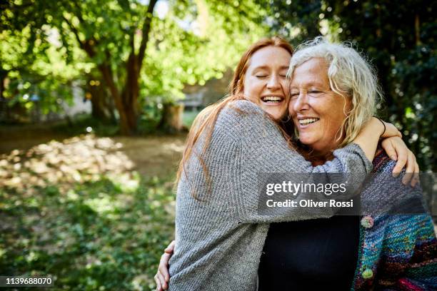 happy affectionate senior woman and young woman in garden - enkelkind stock-fotos und bilder