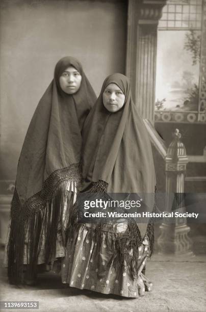 Kate Eagle , left, and her sister Minnie Eagle , Black River Falls, Wisconsin, 1910. Both women are wearing fringed shawls over their heads.