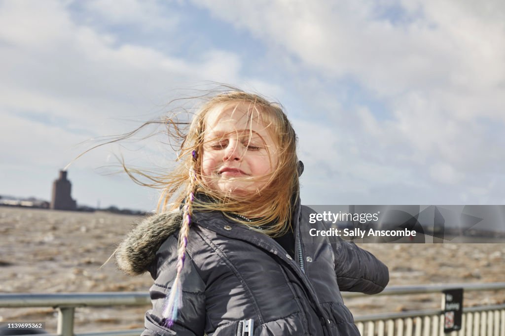 Happy smiling child outdoors with hair blowing in the wind