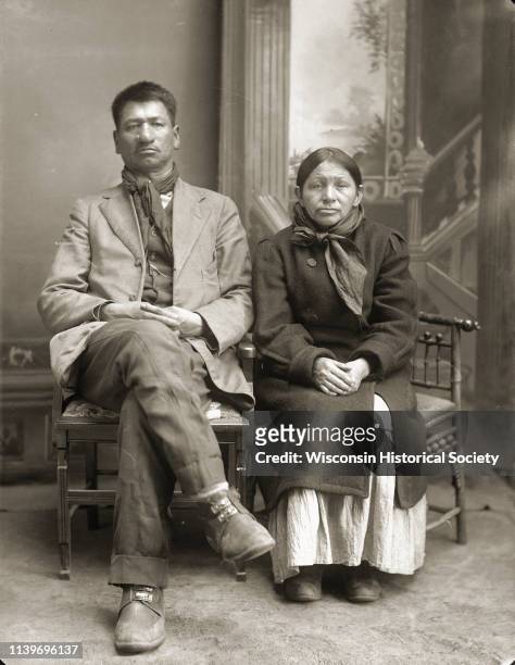 Full-length studio portrait of Thomas Thunder , and his wife, Addie Littlesoldier, Lewis, Thunder , Black River Falls, Wisconsin, 1915. He is wearing...