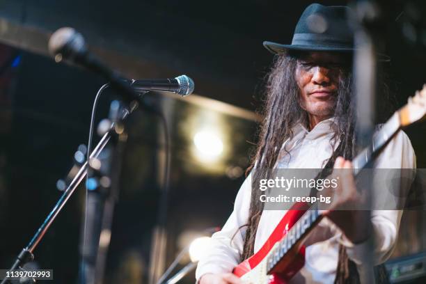 male musician with dreadlocks playing guitar and singing on stage - pop reggae stock pictures, royalty-free photos & images