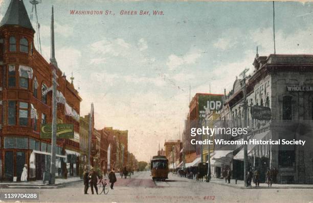 View looking down Washington Street with cable car, bicyclist and pedestrians walking along the sidewalks in downtown area, Green Bay, Wisconsin,...