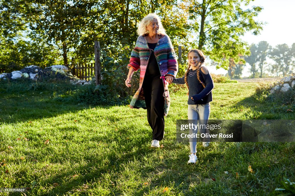 Happy grandmother and granddaughter walking in garden