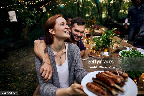 happy couple on a barbecue garden party - eating food happy stockfoto's en -beelden