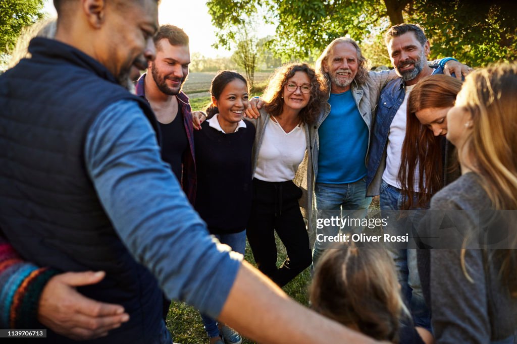 Group of happy people embracing on a garden party at sunset