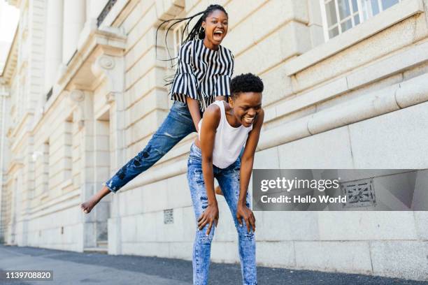 Beautiful gappy friends playing leapfrog barefoot on the pavement