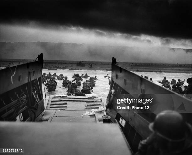 Troops wading through water after reaching Normandy and landing Omaha beach on D Day 1944.