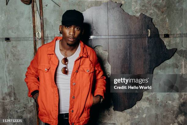 handsome young man looking into camera with africa continent on wall mural behind - hands in pockets stock pictures, royalty-free photos & images