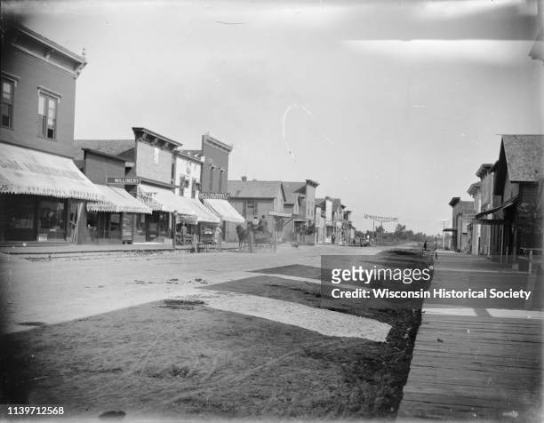 South side of Main Street from the intersection with Merrill Street, Black River Falls, Wisconsin, 1901. Various storefronts are on the left,...