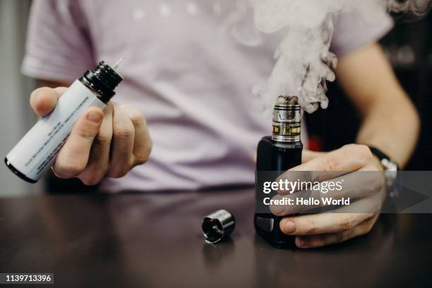 hands illustrating refilling smoking vape on counter top - cigarette électronique photos et images de collection