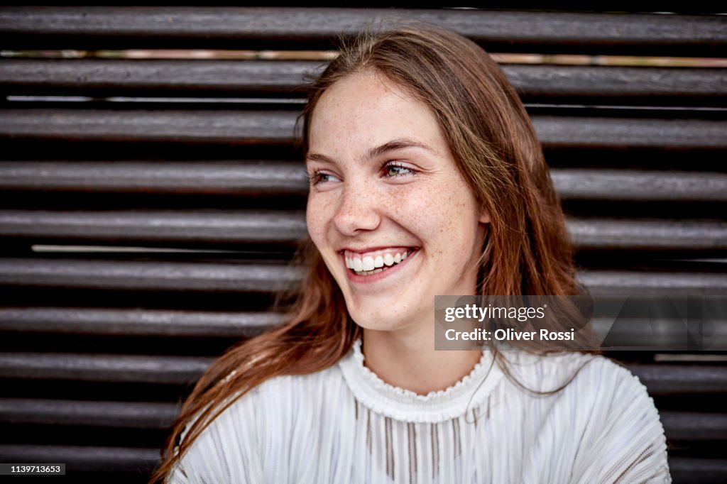 Portrait of happy young woman sitting on a bench