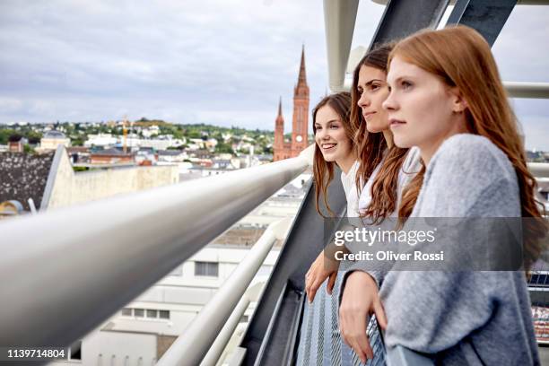 three young women on rooftop looking at the city - städtereise stock-fotos und bilder