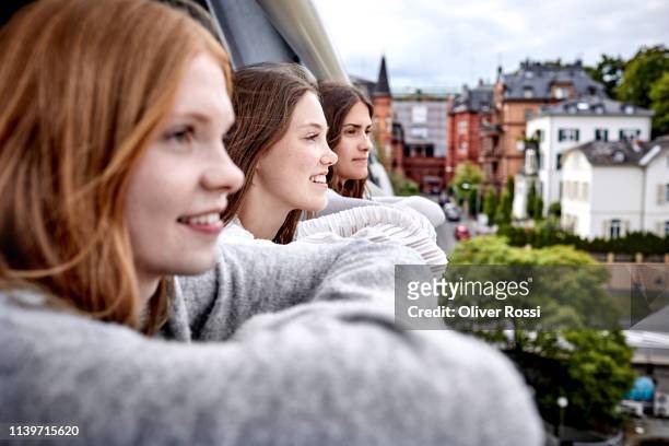 three young women on rooftop looking at the city - dachterasse stock-fotos und bilder