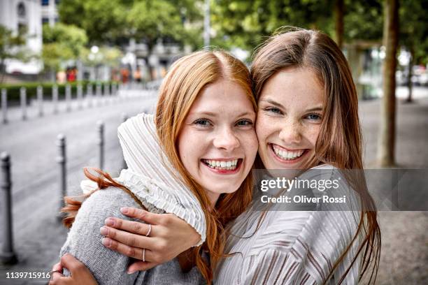 portrait of two happy young women embracing in the city - freundinnen lachen stock-fotos und bilder