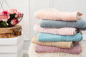 Stack of clean soft colorful towels. Flowers on background