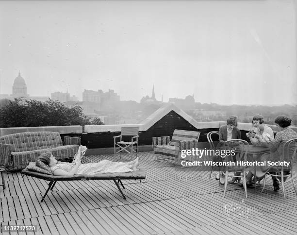 Three University of Wisconsin-Madison coeds are playing cards, and one woman is reading, on the roof of Ann Emery Hall, 265 Langdon Street, an...