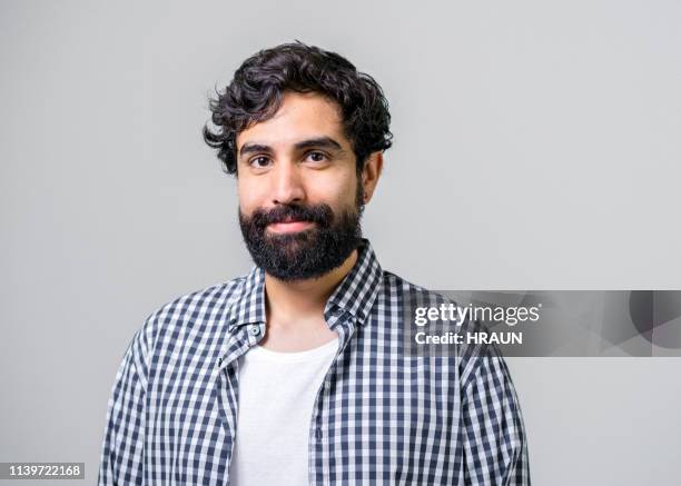 mitteler erwachsener mann lächelt auf grauem hintergrund - man beard stock-fotos und bilder
