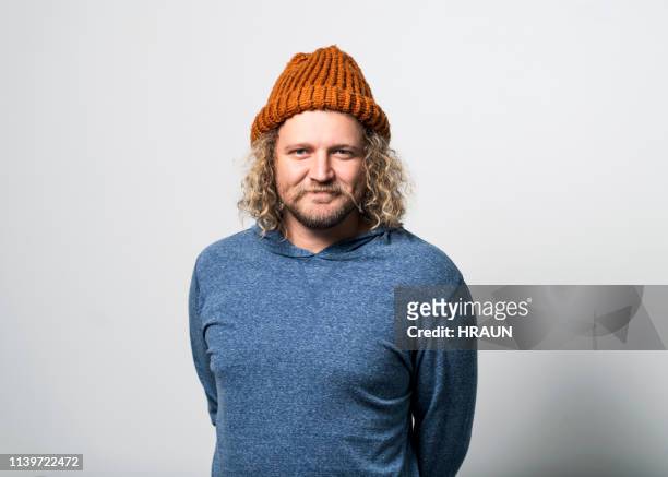 smiling man wearing knit hat on gray background - curly hair isolated stock pictures, royalty-free photos & images