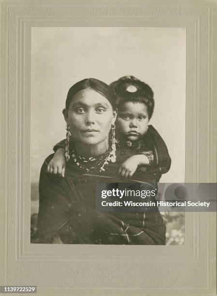 Quarter-length studio portrait of a woman in Ho-Chunk regalia wrapped in a blanket, with a child on her back, Black River Falls, Wisconsin, May 7,...