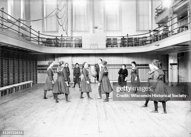 University of Wisconsin-Madison freshman women's basketball team in the gymnasium of Ladies Hall , Madison, Wisconsin, 1900. A man stands in the...