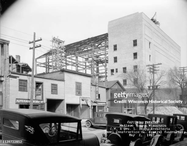 View of Madison businesses on Henry Street, with steel frame construction of the Capitol Theatre in the background, Madison, Wisconsin, May 2, 1927.