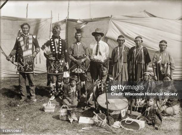Ho-Chunk performers gathered behind a drum and Winnebago baskets at the 1908 Homecoming, Black River Falls, Wisconsin, 1908. Standing from the left...