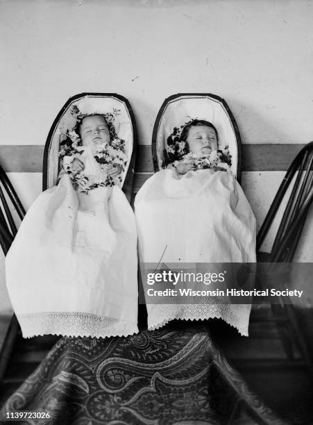 Studio portrait of deceased twin infants in coffins, Black River Falls, Wisconsin, 1886. They are Robert and Janet Fitzpatrick, born July 5 died...