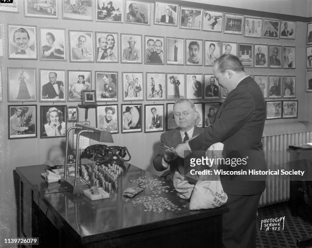 With a backdrop of celebrity portrait photographs and stacks of coins on his desk, Hugh Flannery, manager of the Orpheum Theatre, is receiving a $100...