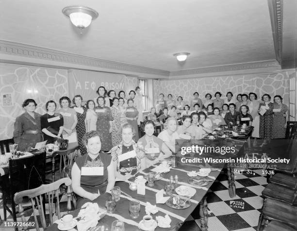 Group portrait of Alpha Epsilon Phi sorority members standing around banquet tables at senior breakfast, 22 Langdon Street, Madison, Wisconsin, May...