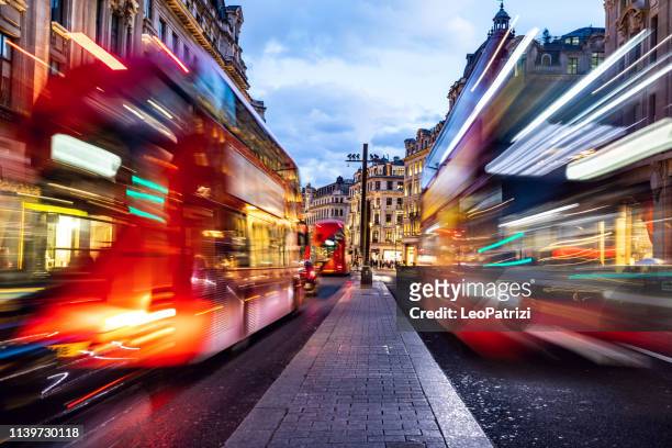 londons typischer roter bus verschwimmt bewegung in der nacht im oxford circus - oxford street stock-fotos und bilder
