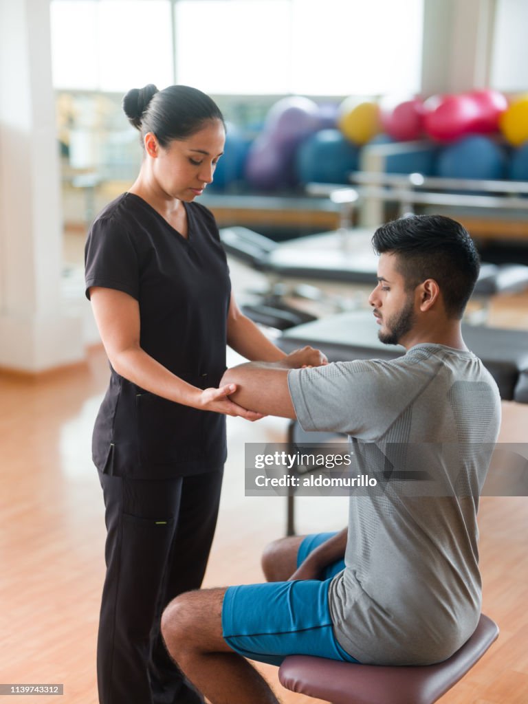 Terapeuta de masaje comprobando el brazo del paciente