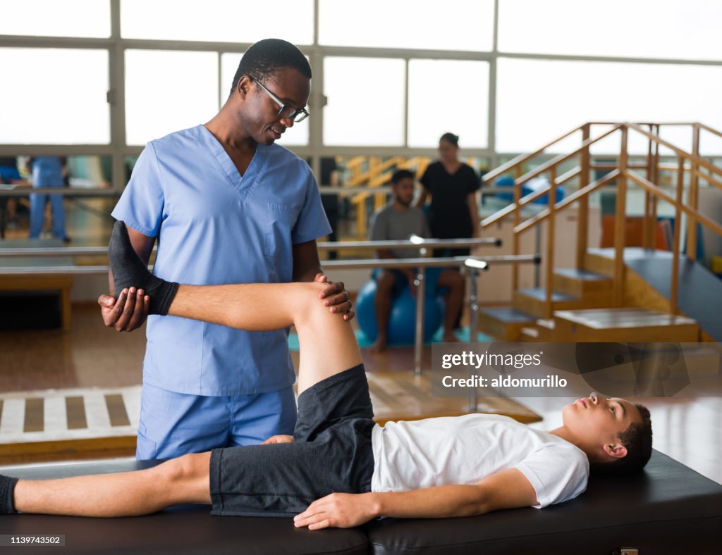 Tonårspojke ligger på massage bordet och få sjuk gymnastik
