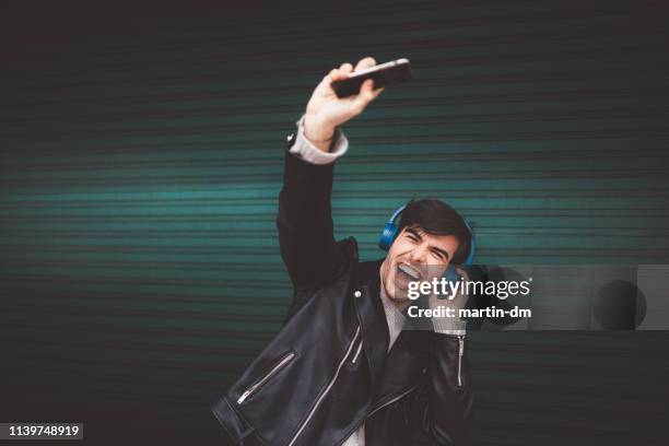 luisteren naar muziek - young man listening to music on smart phone outdoors stockfoto's en -beelden