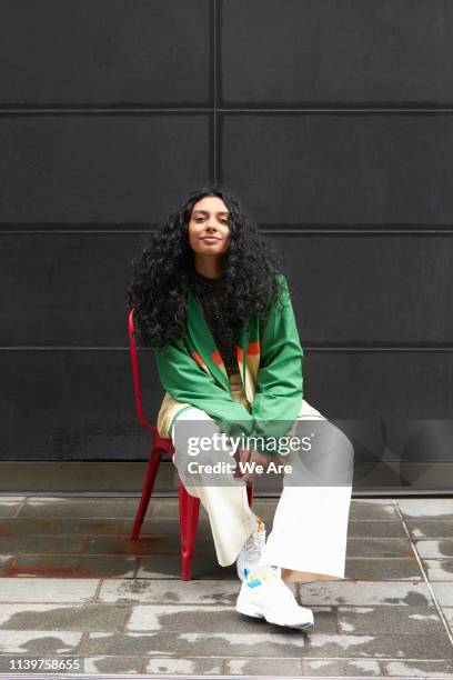 young fashionable woman on red chair - effortless stock-fotos und bilder