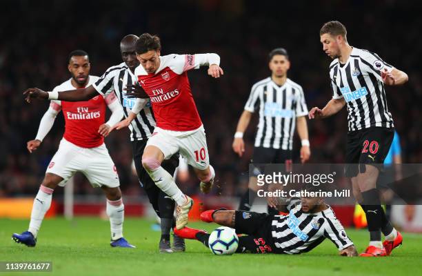 Mesut Ozil of Arsenal evades Mohamed Diame, Deandre Yedlin and Florian Lejeune of Newcastle United during the Premier League match between Arsenal FC...