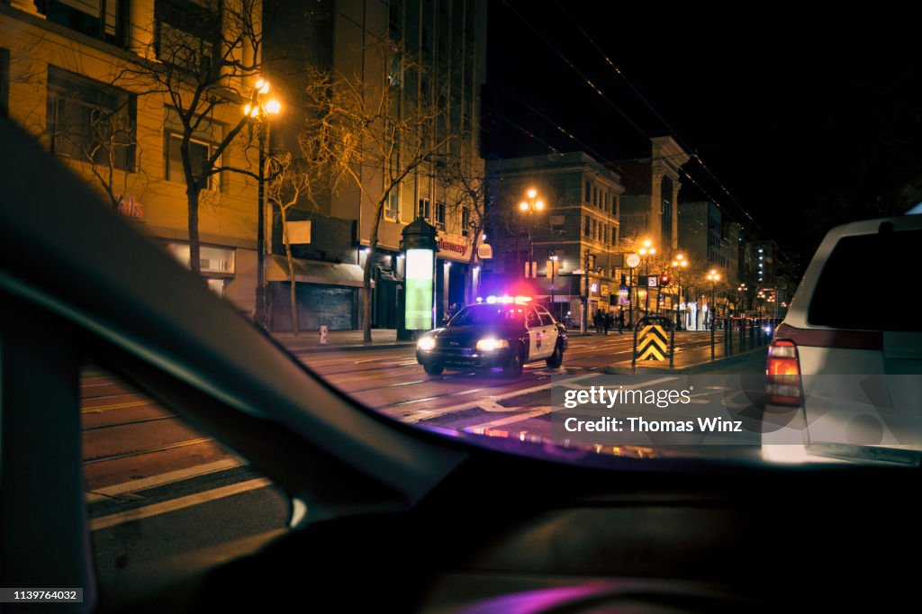 Police car with emergency lights on in downtown district