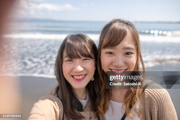 young female friends taking selfie pictures in front of pacific ocean - photographing self stock pictures, royalty-free photos & images