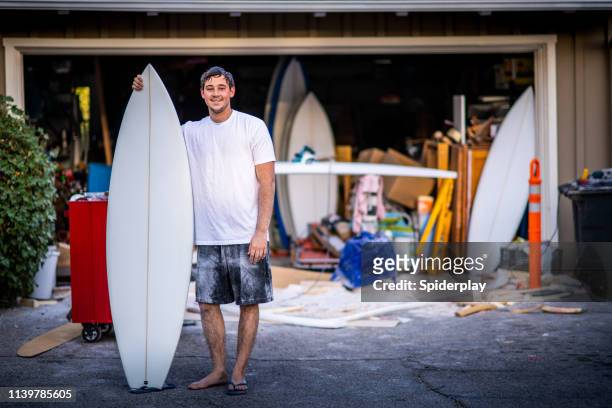 empreendedor apaixonado novo que mostra fora seu surfboard feito encomenda terminado - ambientação - fotografias e filmes do acervo